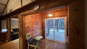 Ein gemütliches Blockhauskaminfeuer mit Holzboden, einer Bank und einem Essbereich mit Tisch und Stühlen.