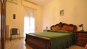 A bedroom with a bed, a chair, a nightstand, a lamp, a radiator, and a picture on the wall. - A few steps from the sea (Marina di Grosseto)