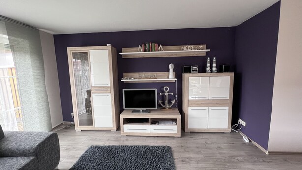 Een woonkamer met een televisie, een boekenkast en een kast.
