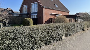 Een tweelaags bakstenen huis met een schuin dak, een omheinde achtertuin en een verharde oprit.
