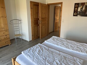 Une chambre avec deux lits, une armoire en bois et une chaise.
