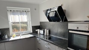 Een moderne keuken met een inbouwfornuis, een spoelbak en een raam met gordijnen.