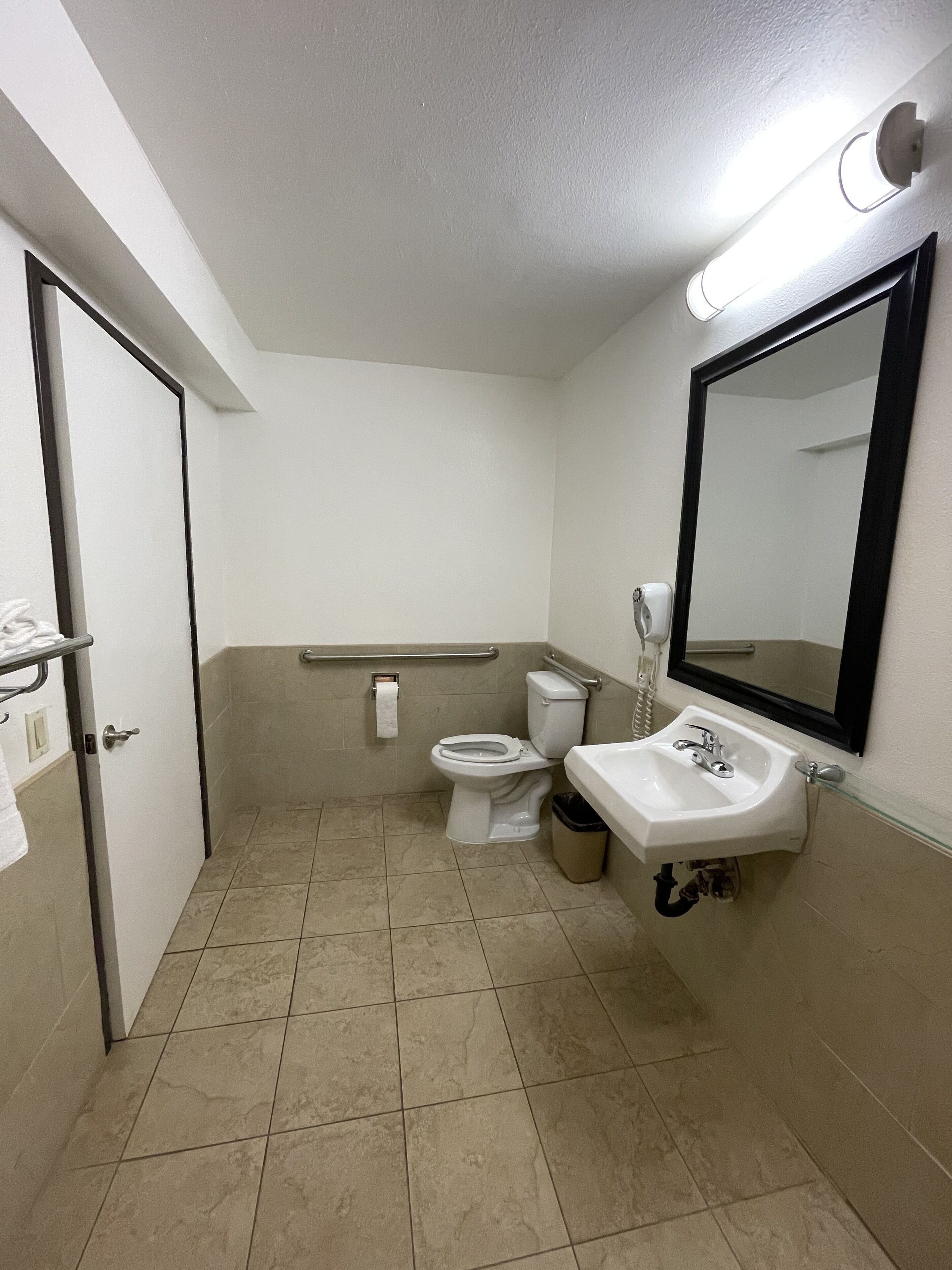 A small, clean bathroom with a toilet, sink, and mirror.