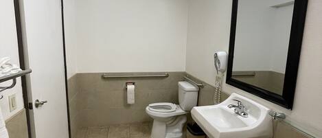 A small, clean bathroom with a toilet, sink, and mirror.