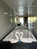 Un baño moderno con una bañera grande, un espejo y una encimera de mármol.