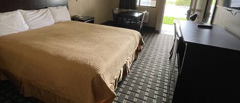 Habitación de hotel con una cama grande, un escritorio, una silla y un televisor.