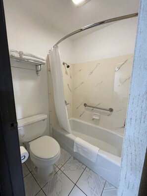 A bathroom with a toilet, a bathtub, and a shower curtain.