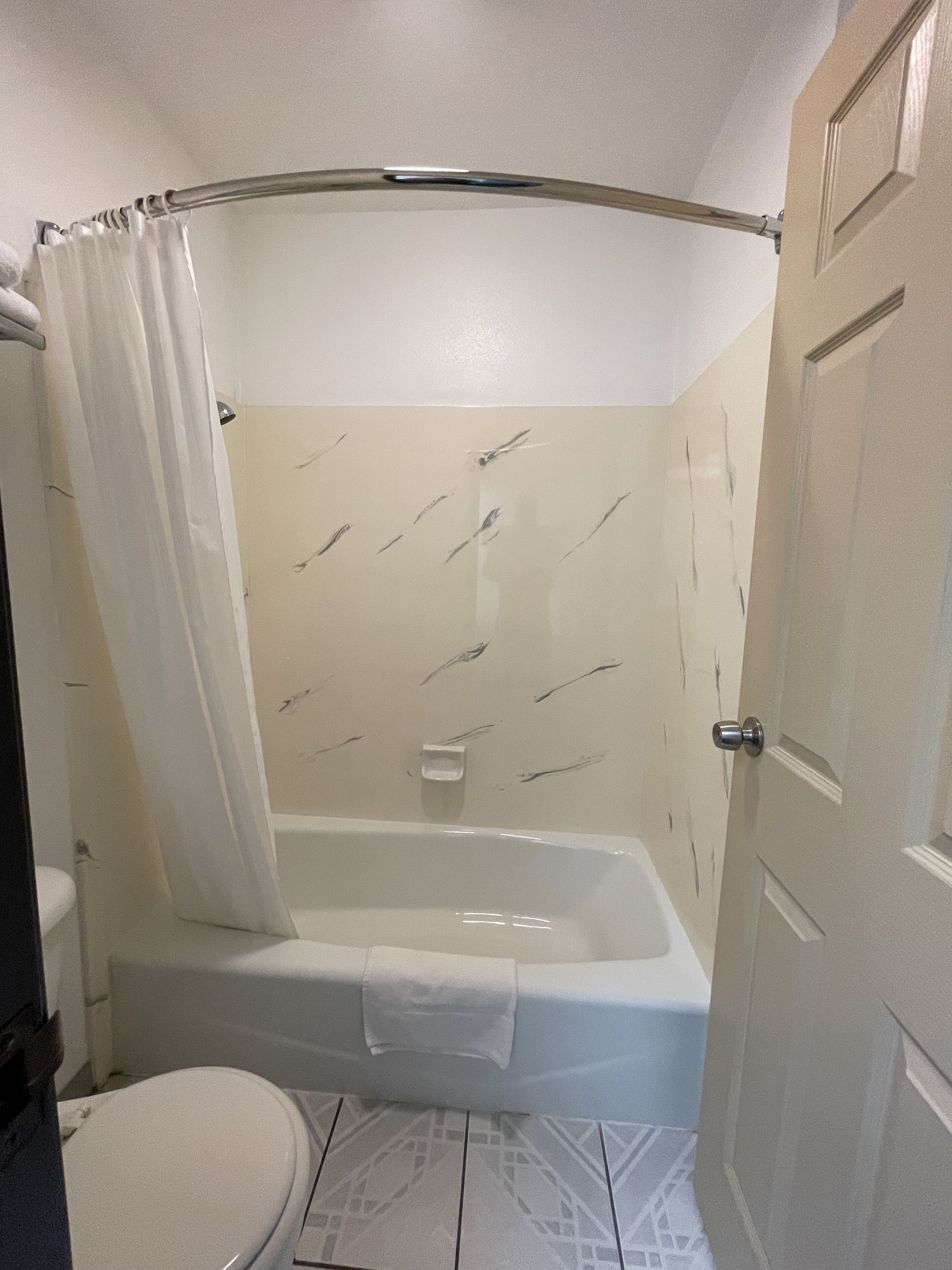 A bathroom with a bathtub, toilet, and shower curtain.