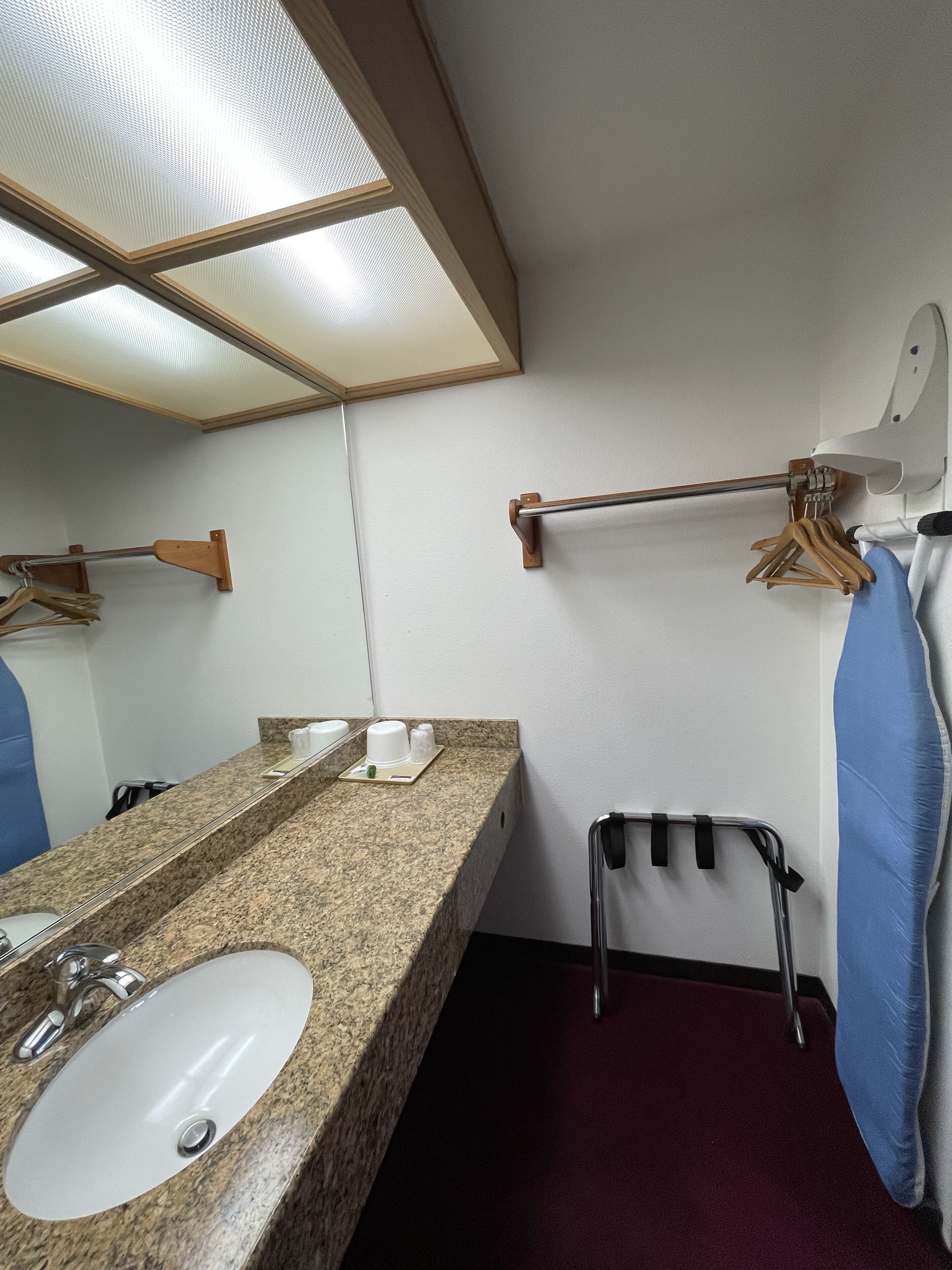Un baño con lavamanos de encimera de granito, espejo, toallero y cortina de ducha.