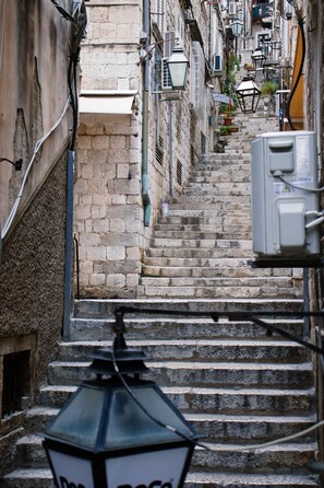 Eine enge Steintreppe führt zu einem Gebäude mit mehreren Fenstern und einer weißen Markise.