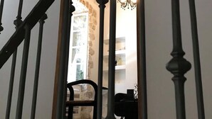 A staircase with a wooden handrail and black balusters leading to a room with a chandelier, a chair, and a black sofa. - Lovely 1-bed Apartment Niko in Dubrovnik (Dubrovnik)