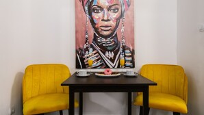 A dining area with two yellow chairs, a table, and a colorful painting on the wall. - Lovely 1-bed Apartment Niko in Dubrovnik (Dubrovnik)