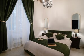 Une chambre à coucher bien rangée, avec un grand lit, une lampe de chevet, un miroir et un ordinateur portable posé sur le lit.