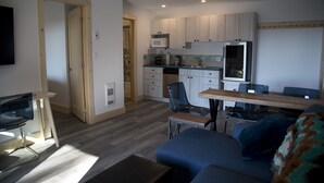 A compact living space with a kitchenette, a dining area, and a seating area with a sofa and a table. - West Coast Oceanfront Private Suite with Stunning View (Ucluelet)