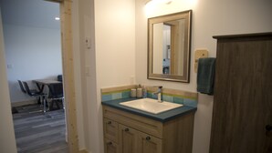 A bathroom with a sink, mirror, and wooden cabinet. - West Coast Oceanfront Private Suite with Stunning View (Ucluelet)