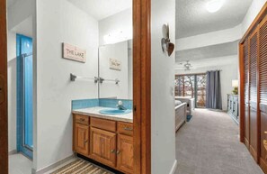Ein Badezimmer mit einem Holztischchen, einem blauen Waschbecken und einem Spiegel.
