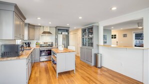 Una cocina moderna con suelo de madera, electrodomésticos de acero inoxidable y armarios blancos.