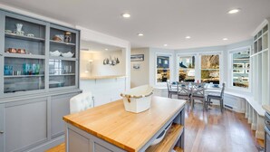 Una cocina con mostrador de madera, armarios empotrados y vistas al exterior gracias a amplias ventanas.