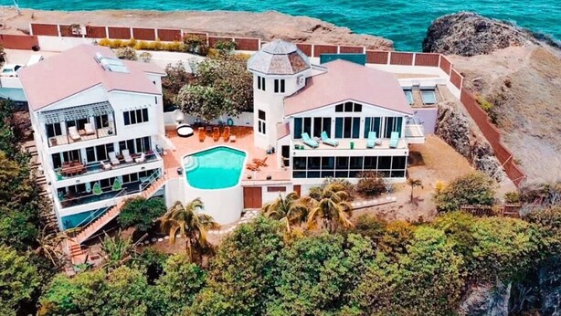 A two-story resort with a swimming pool, multiple balconies, and a view of the ocean.