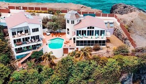A two-story resort with a swimming pool, multiple balconies, and a view of the ocean. - The Reef Villa is two bedrooms with en-suite bathrooms  (St Georges)