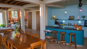 A spacious kitchen with a blue island, wooden bar stools, and a dining area with a wooden table and chairs.