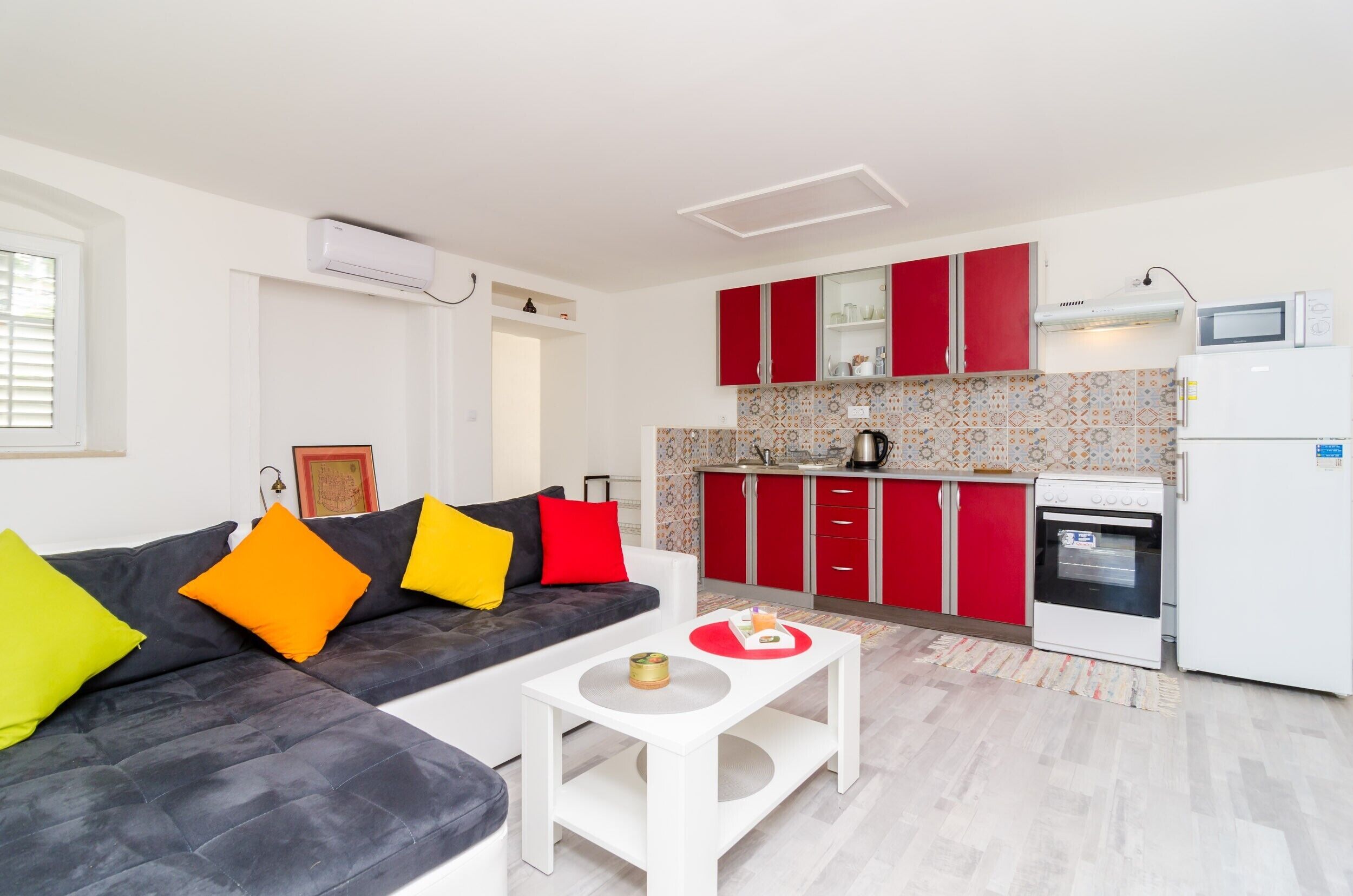 A modern kitchen with red cabinets, a white refrigerator, and a microwave.