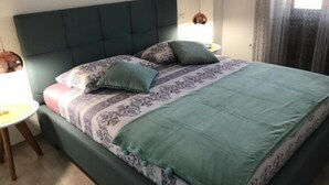 A neatly made bed with a patterned bedspread and pillows, a dark headboard, and bedside lamps.