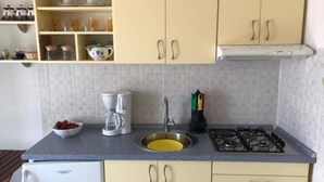A compact kitchen with a sink, stove, and white cabinets.
