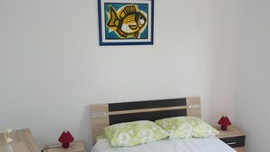 Une chambre à coucher bien rangée, avec un lit, deux tables de chevet et une œuvre d’art accrochée au mur.