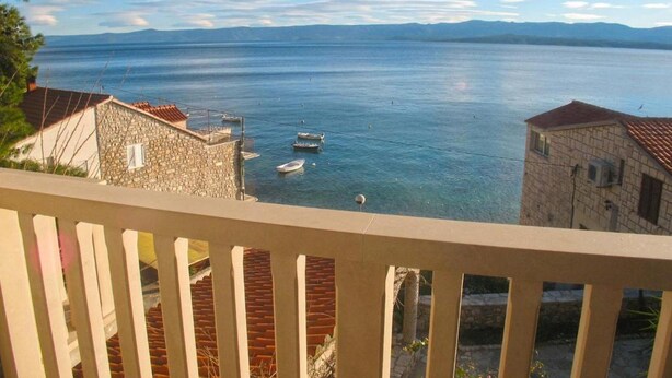 Une vue sur la côte, avec des bâtiments en pierre, une mer d’un bleu limpide et des bateaux.