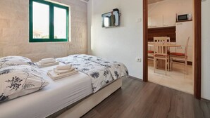 A bedroom with a bed, a window, a television, and a view of a dining area. - Apartments Vujina - Studio 3 (Kastel Stafilic)