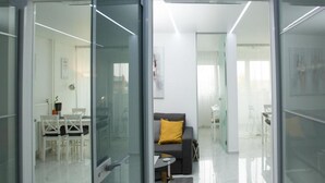 Een moderne, goed verlichte kamer met een glazen deur naar een eetgedeelte en een zithoek.