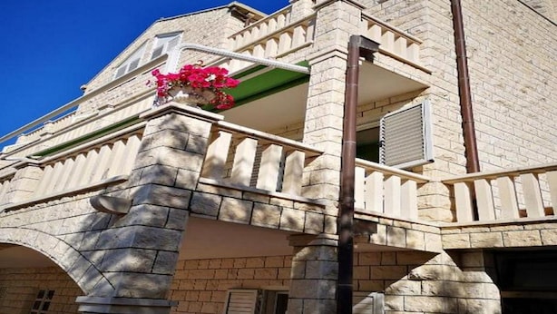 Un edificio de piedra con un balcón, una chimenea y un arreglo floral.