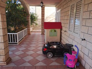 A covered outdoor area with a tiled floor, a toy car, and a toy car seat.