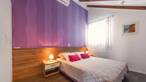 Une chambre à coucher avec une tête de lit en bois, un lit recouvert d’une couvre-lit à motifs, deux lampes de chevet et une table de chevet dotée d’un tiroir.