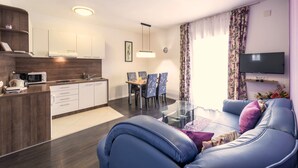 Ein modernes Wohnzimmer mit einem blauen Sofa, einem Glastisch und einem Flachbildfernseher.