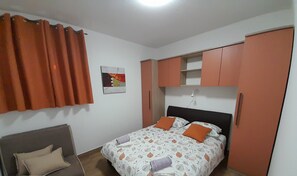Een slaapkamer met een bed, een bank en een kledingkast.