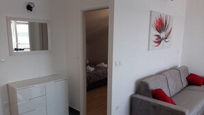 Ett modernt vardagsrum med en grå soffa, ett vitt skåp och en tavla på väggen.