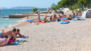 Una spiaggia con persone che prendono il sole e nuotano.