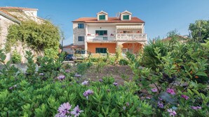 Un edificio a due piani con un balcone e un giardino in primo piano.