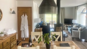 A cozy living room with a wooden dining table, white chairs, a sofa, and a TV. - Step into the Cart House and you will feel instantly at ease. (Duns)
