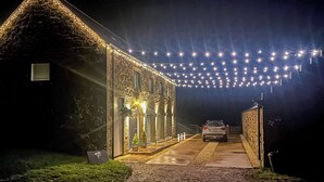 A stone building with a covered walkway, string lights, and a parked car. - Step into the Cart House and you will feel instantly at ease. (Duns)