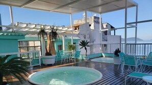 Un área de piscina en la azotea con cubierta de madera, sillas turquesa y piscina circular.