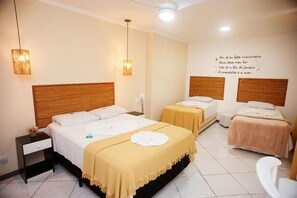 Ein Hotelzimmer mit zwei Betten, einem Nachttisch, einem Wandbild mit einem dekorativen Zitat und einem Deckenventilator.