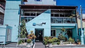 Un edificio con fachada azul, un letrero que dice "em cantina" y macetas con plantas en la entrada.
