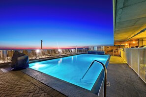 A rooftop pool with a clear view of the city skyline at dusk.