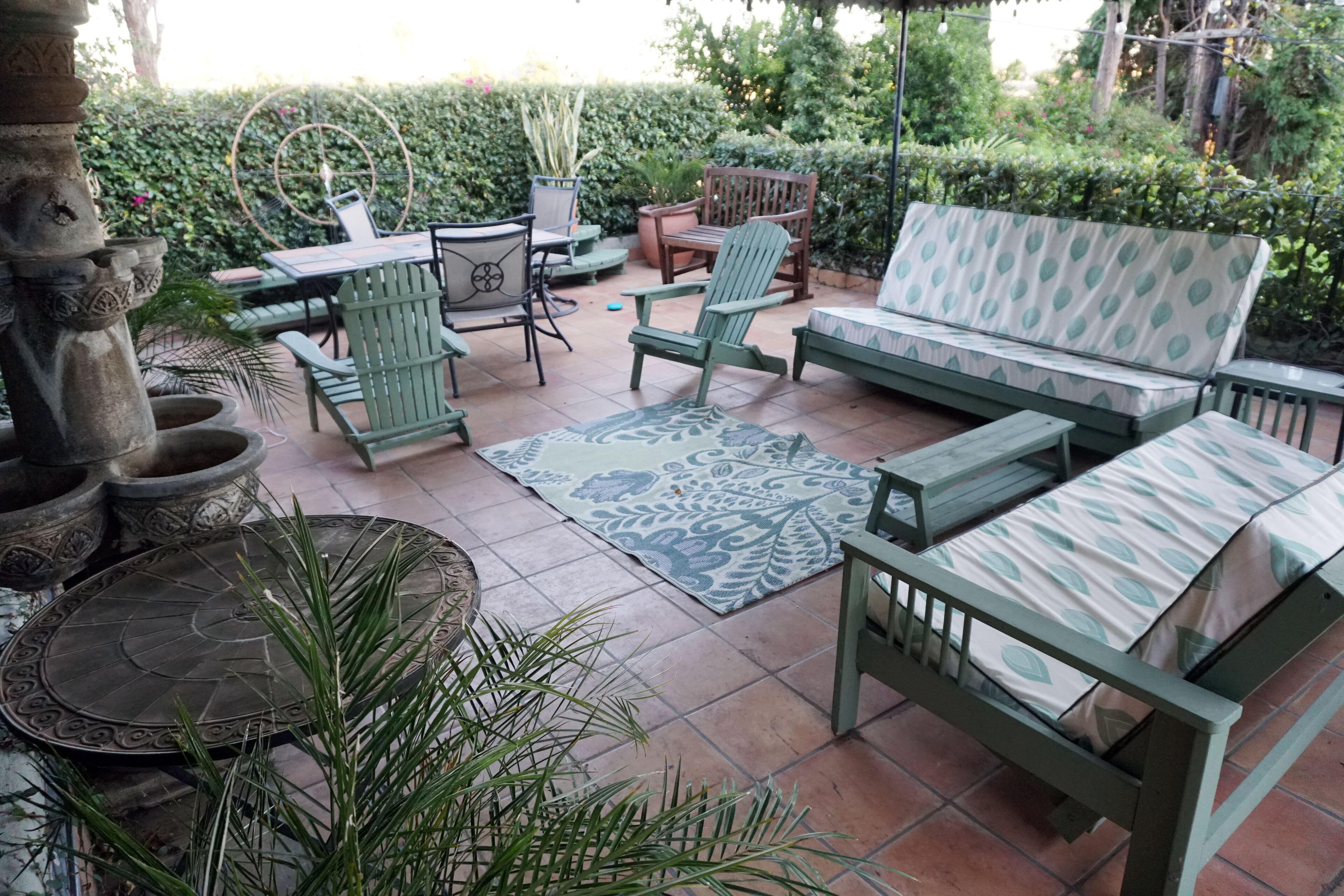A patio area with a sofa, chairs, a table, and potted plants.