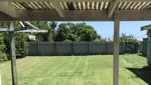 Een overdekt terras met een betonnen vloer en een houten picknicktafel.