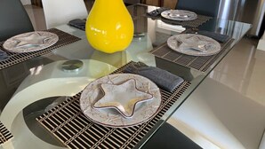 Una cucina moderna con un tavolo da pranzo in vetro, elettrodomestici in acciaio inossidabile e un vaso decorativo giallo.