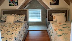 Una camera da letto con due letti, un soffitto spiovente e una finestra con persiane.